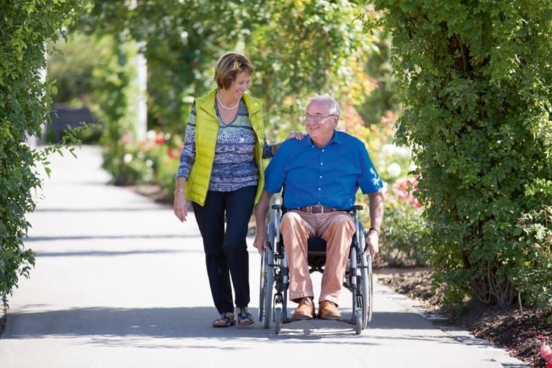 Ein Mann im Rollstuhl ist mit einer Frau unterwegs
