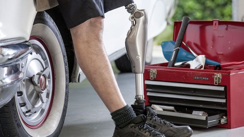 Ein Mann mit einer Prothese steht neben einem Werkzeugkasten