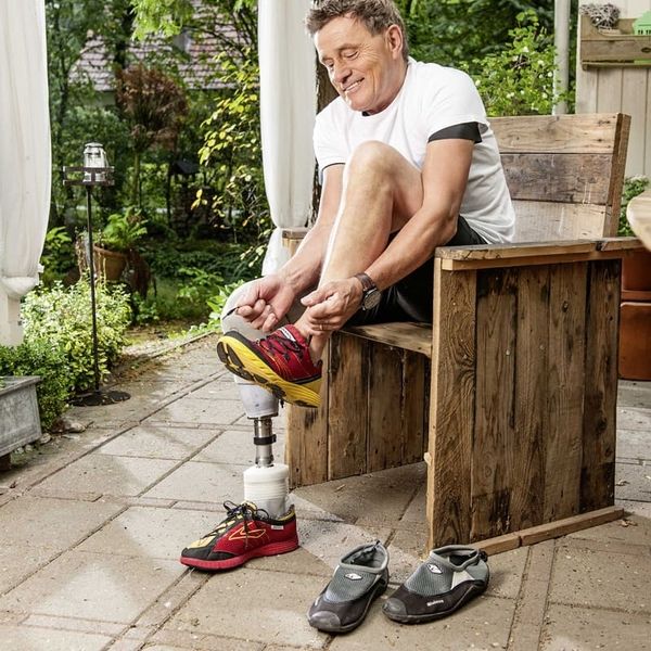 Ein Mann mit Prothese bindet sich die Schuhe zu