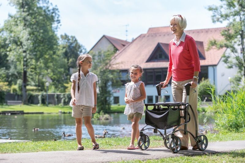 Eine ältere Dame mit einem Leichtgewichtrollator und mit 2 Kindern