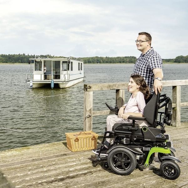Eine Frau im Rollstuhl und ein Mann sind am Wasser