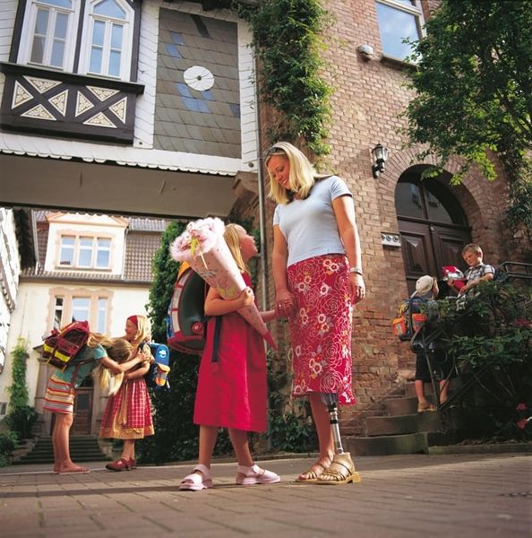 Eine Frau mit einer Prothese und ein Kind erleben den ersten Schultag