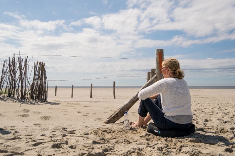 Eine Frau sitzt auf einem Sitzkissen am Strand